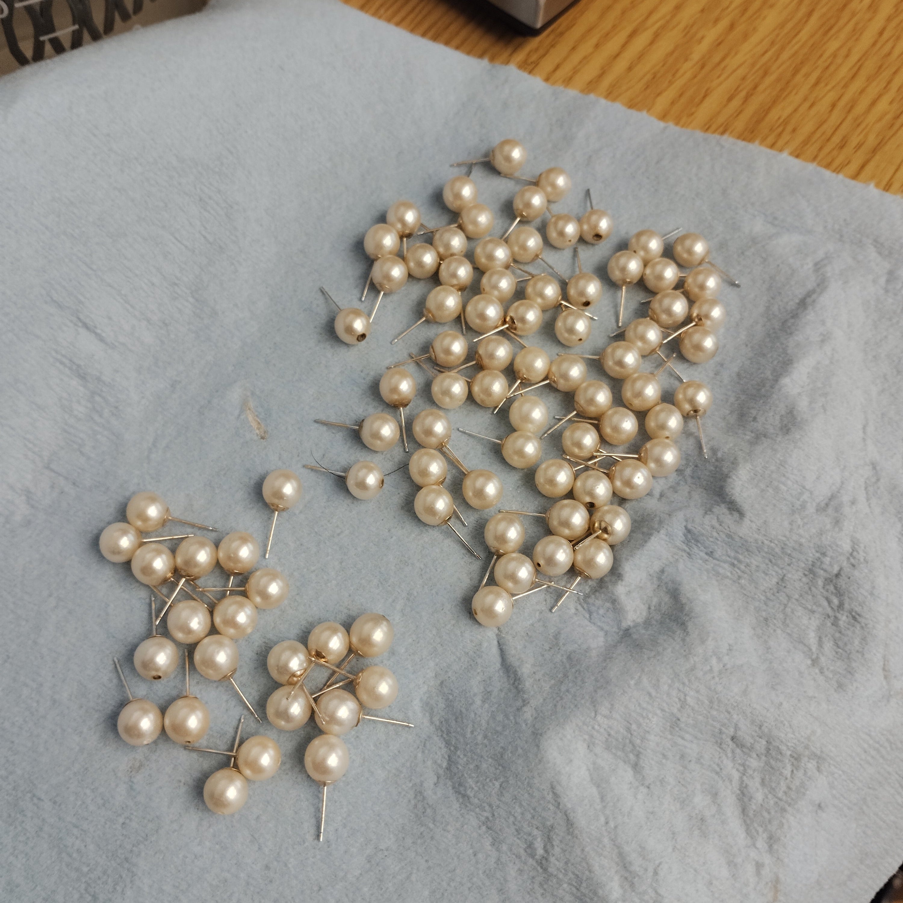 Cleaned natural pearls with mounted 10k yellow gold earring posts, showing visible top through-drilled holes prior to cap installation on a jeweler's bench at Motek Jewelry