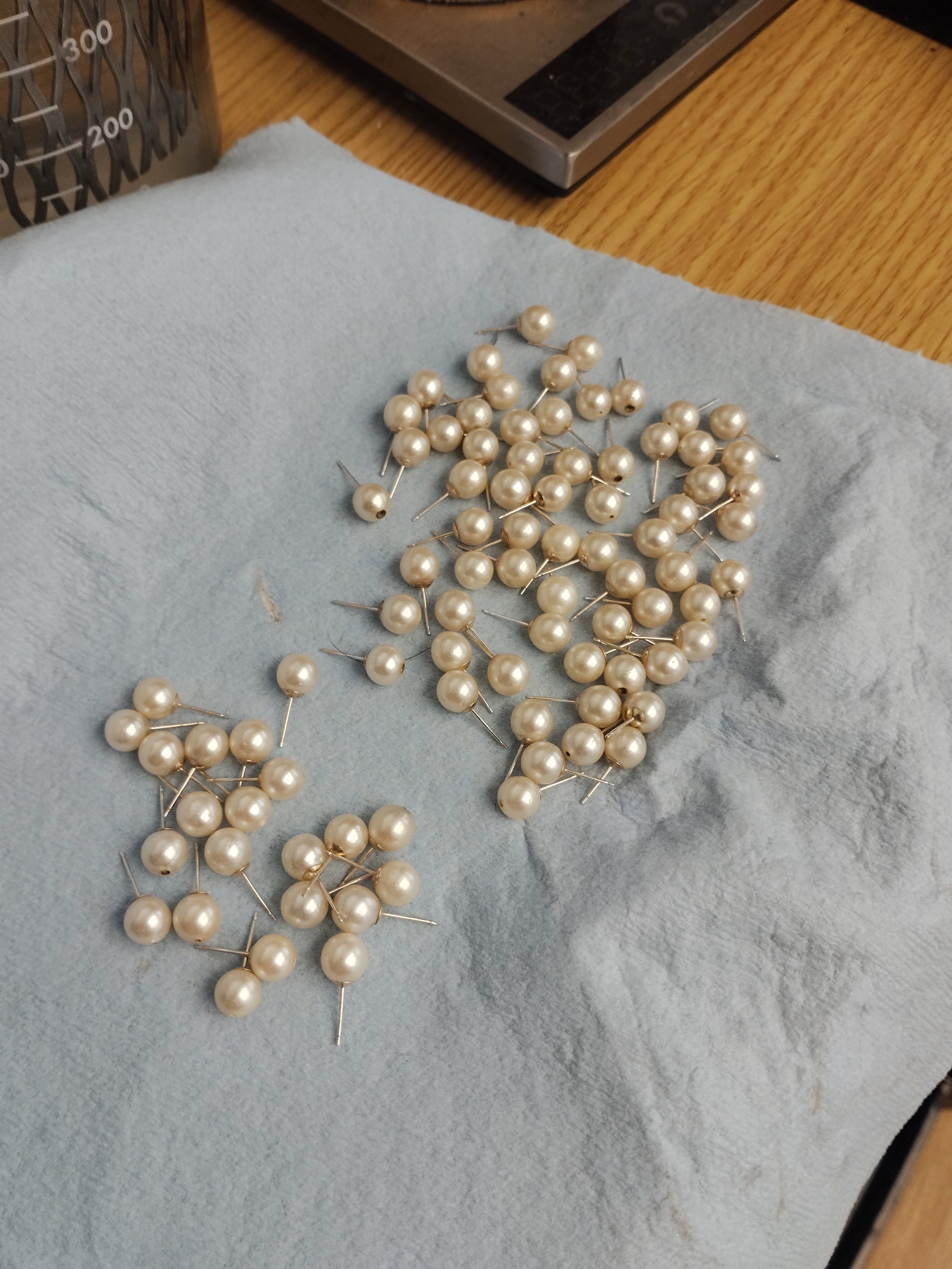 Cleaned natural pearls with mounted 10k yellow gold earring posts, showing visible top through-drilled holes prior to cap installation on a jeweler's bench at Motek Jewelry