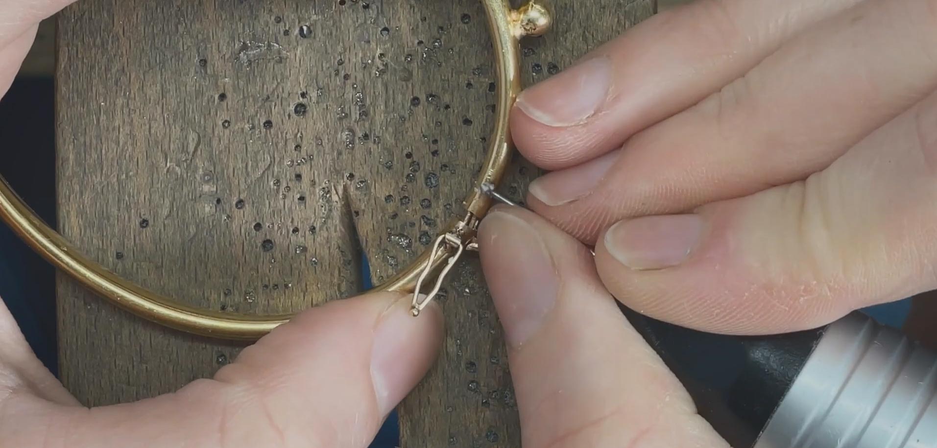 Macro view of a reinforced gold figure-8 safety catch on a fine jewelry bracelet clasp.