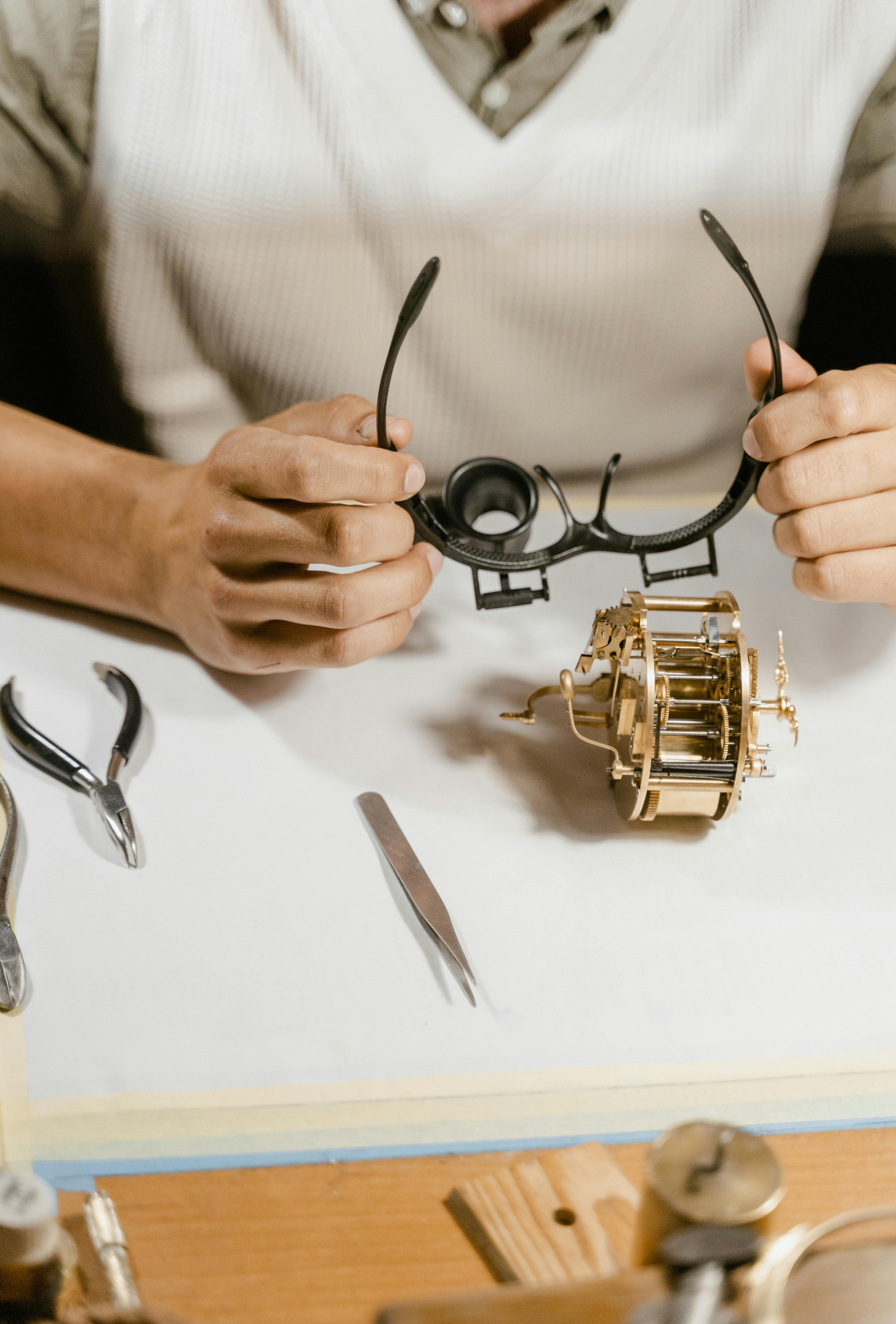 Image of a jeweler meticulously examining a piece of jewelry with tools (loupe, tweezers, scale) on a clean white background