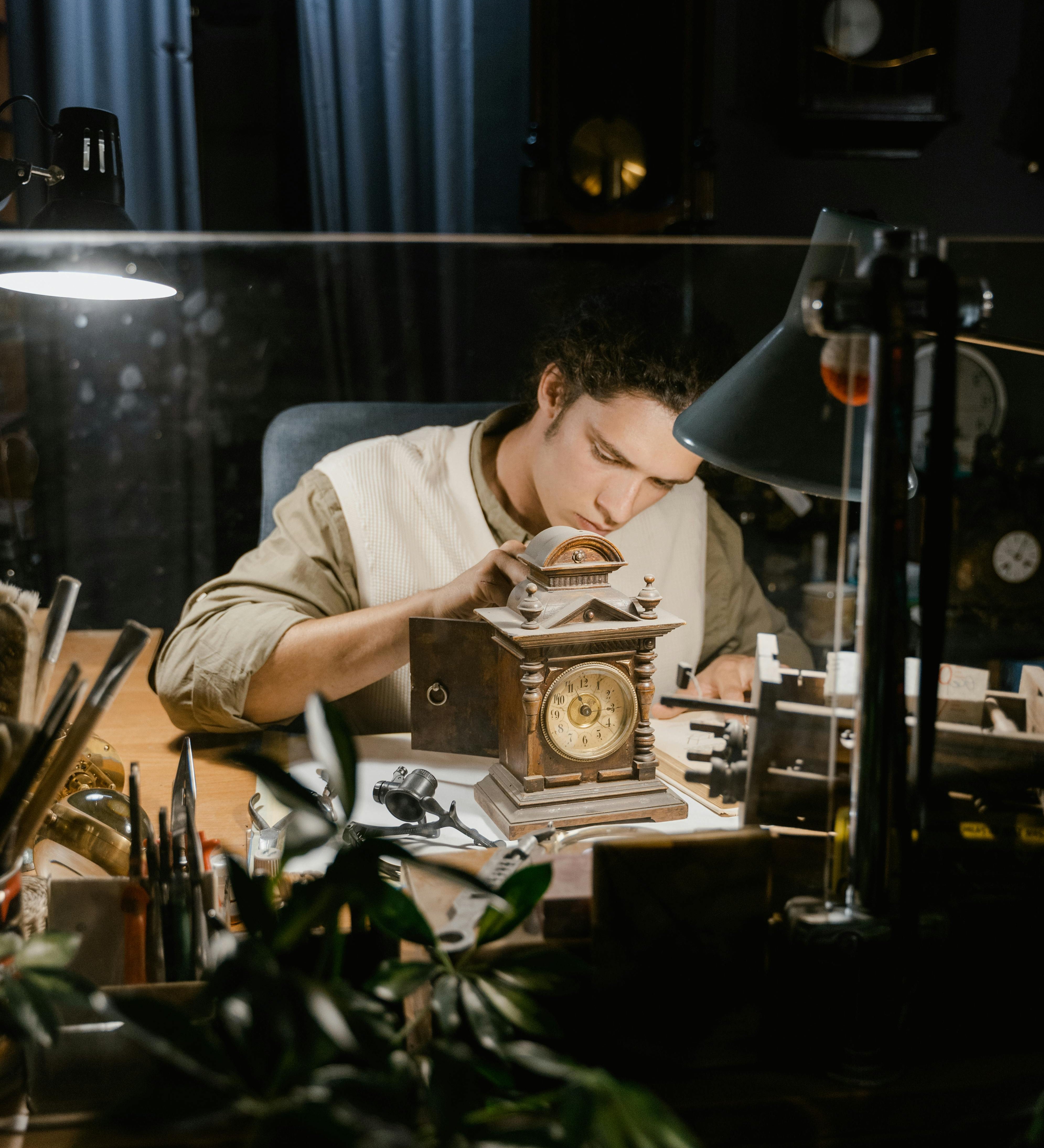 Image of a jeweler in a private consultation setting, leaning over a desk with a client, sketches, and loose gems, emphasizing personal interaction